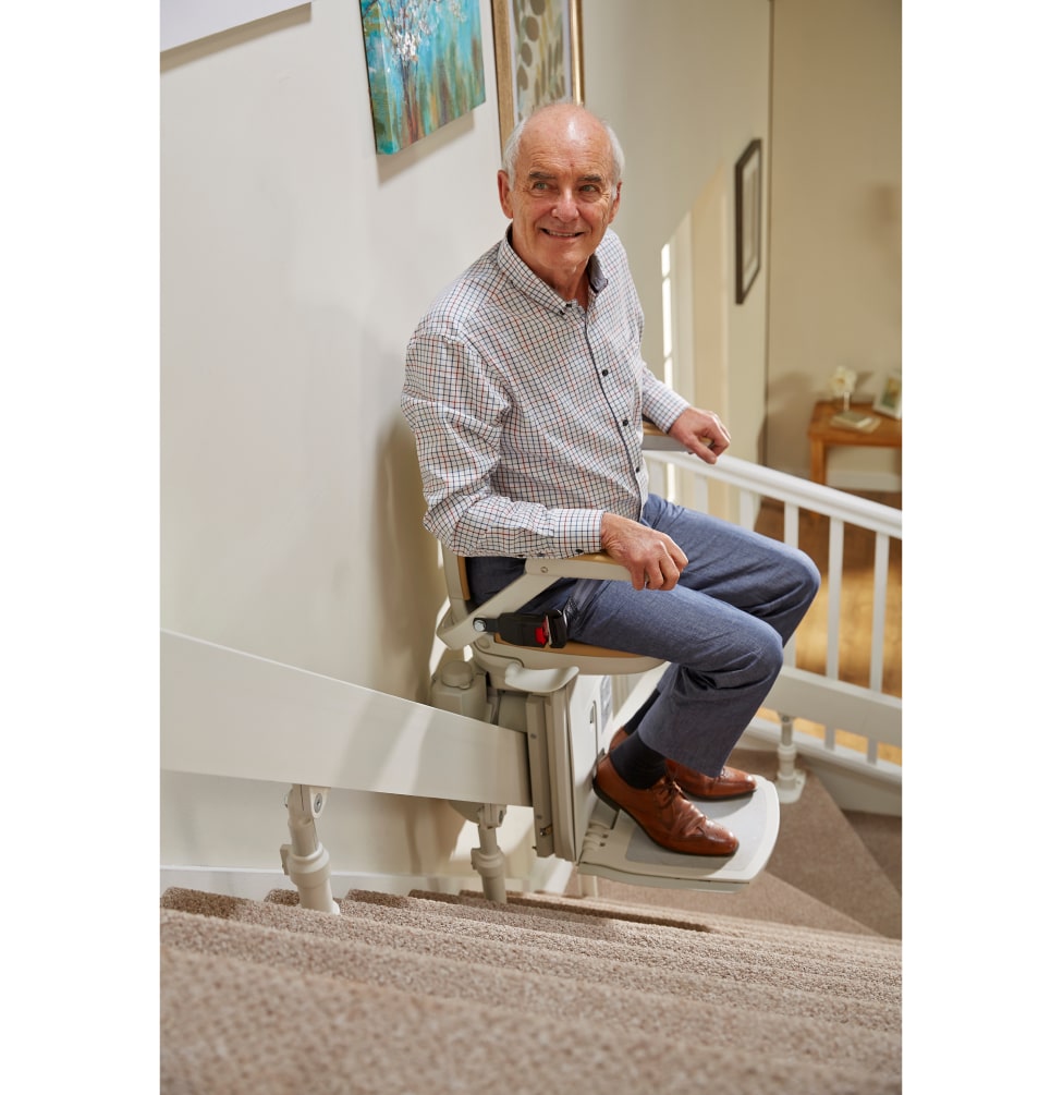 Man riding curved stairlift up the stairs to the top